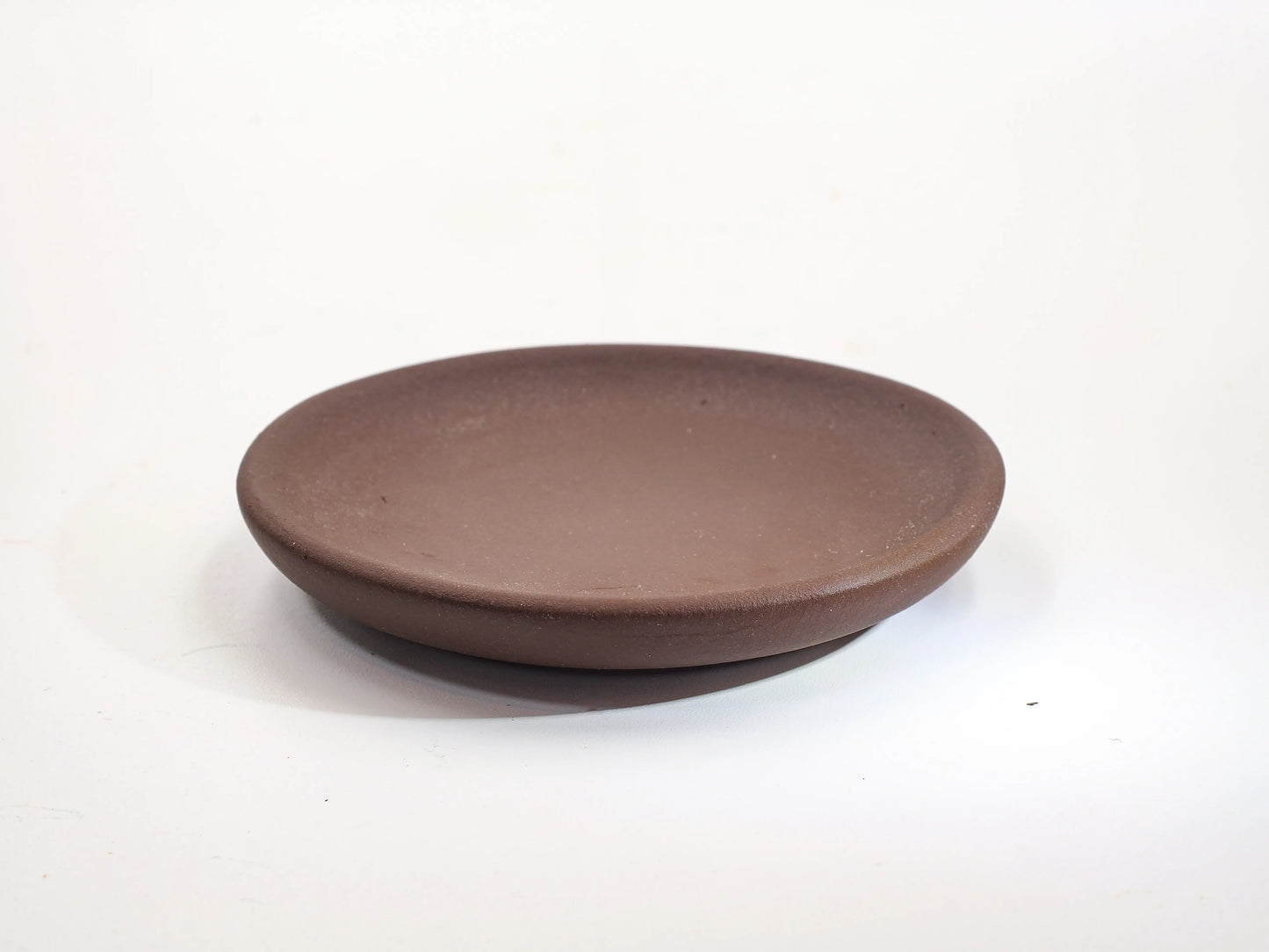Cha Zhi Ji 30th Anniversary Bronze Grade Clay Dehou Coaster, showing the rustic matte texture and thick rim profile.