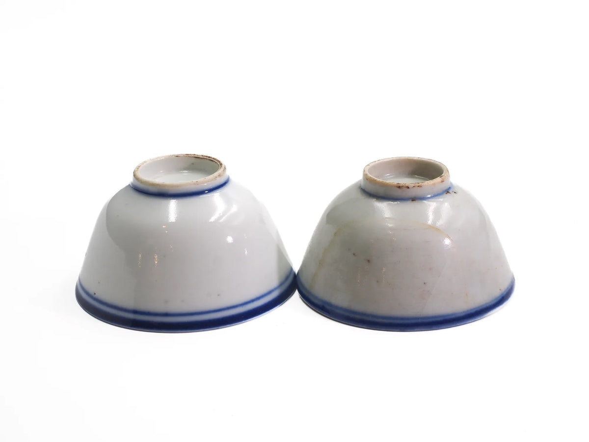 Two upturned antique Late Qing Dynasty Blue Line cups side by side showing foot rings and blue bands, each cup unique in condition