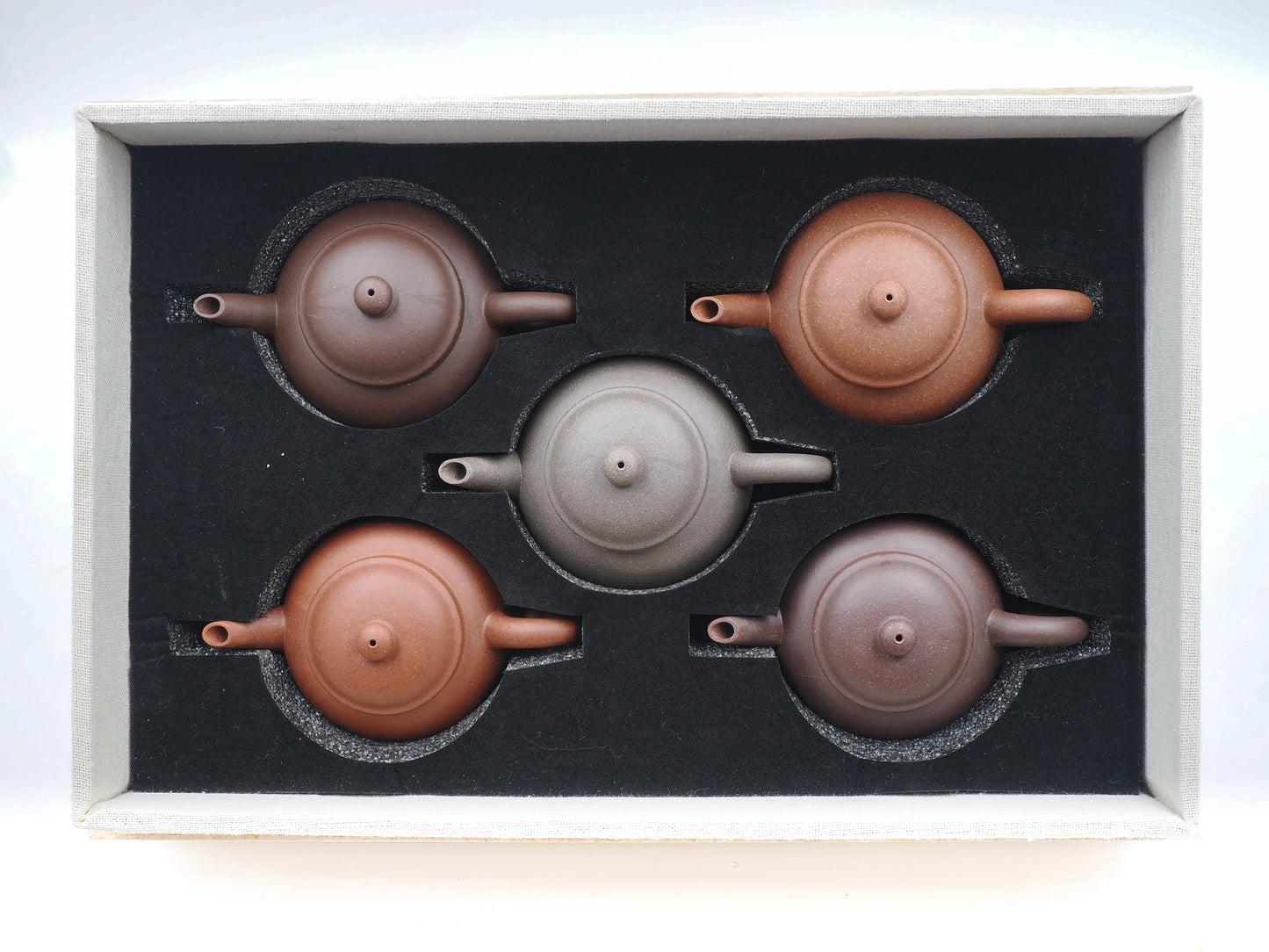 Top-down view of the five anniversary teapots securely nestled in the custom foam-lined collector's box.
