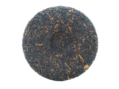 Back view of the unwrapped 2008 Wuliang Gushu Pu-erh Tea Cake showing pressed tea leaf surface
