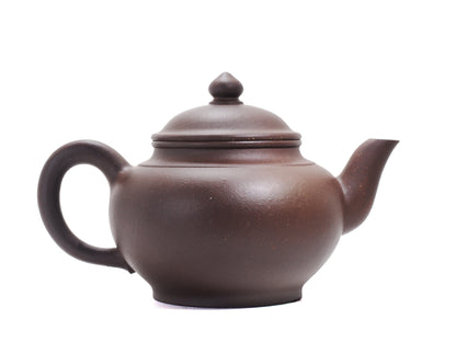 Side view of the bronze‑grade Xiao Ying teapot showing its oblate body, upward‑curved handle and spout and the pointed cherry‑shaped lid knob.