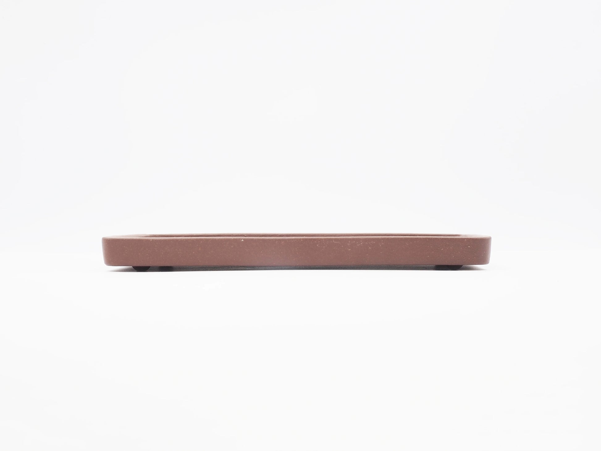 Side profile of the Yixing clay tea tray showing its low, thin form
