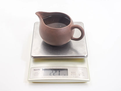 Yixing zisha cha hai filled with water on a scale, showing about 221 ml capacity