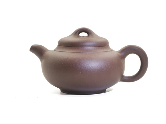 Side view of the Yun Tong Hu Yixing teapot, 260 ml, in bronze-grade purple clay (zisha), showing the low rounded body, short spout, round handle and loop-knob lid